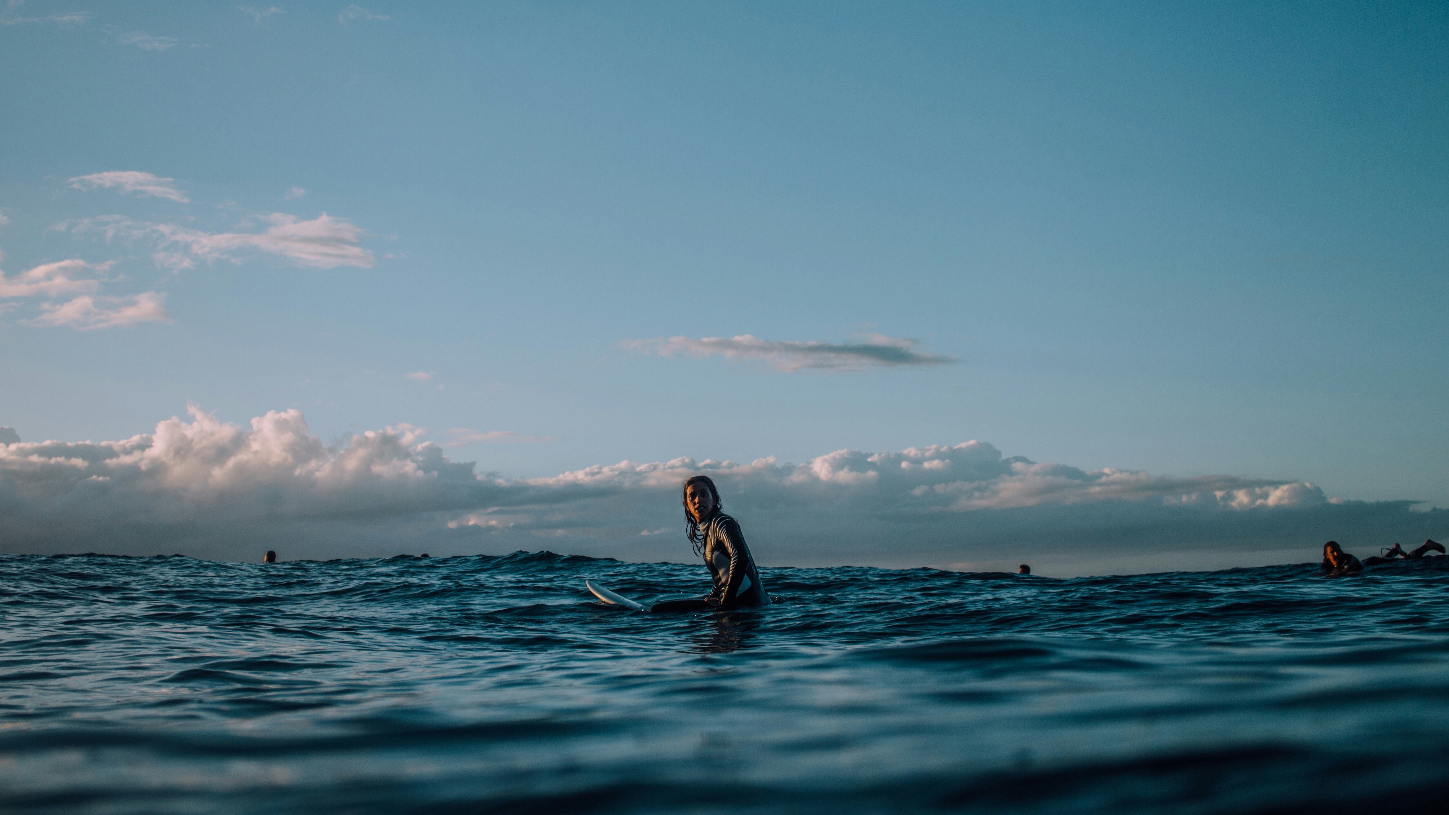 Person Sitting On Surfboard Surrounded By Blue Ocean During