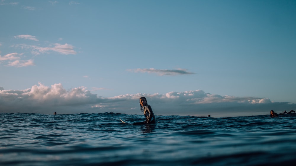 personne assise sur une planche de surf entourée par l’océan bleu pendant la journée