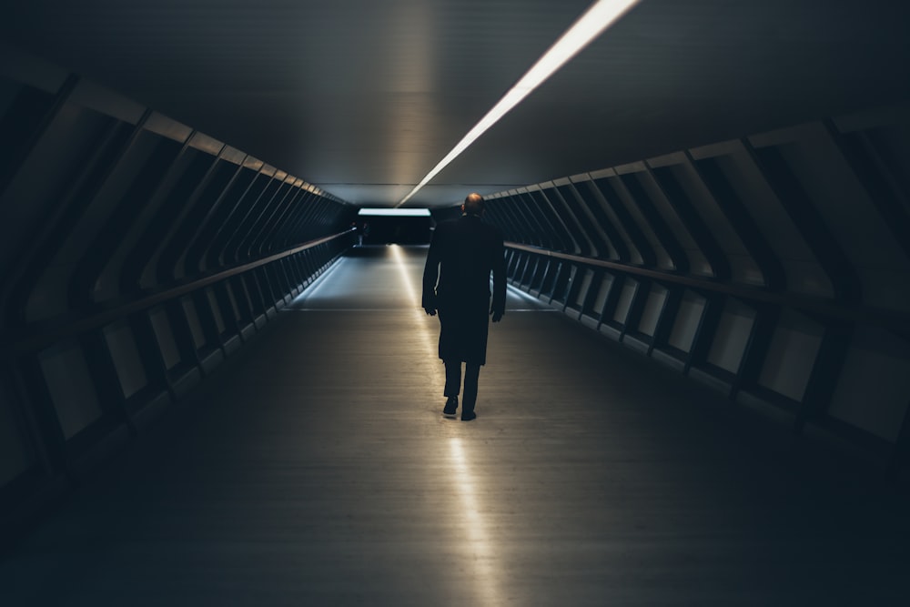 검은 긴팔 셔츠를 입은 사람이 터널을 걷고 있다