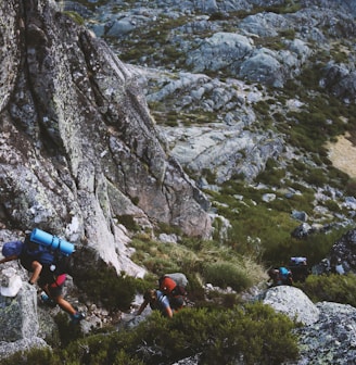 several mountain climbers on cliff of rock mountain at daytime