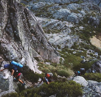 several mountain climbers on cliff of rock mountain at daytime