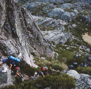 several mountain climbers on cliff of rock mountain at daytime