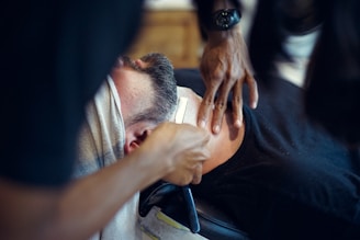 Close-up of a barber applying a hot towel to a client's face before a shave.