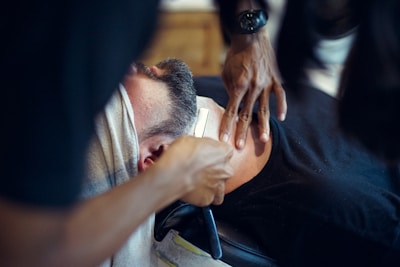 Close-up of a barber applying a hot towel to a client's face before a shave.