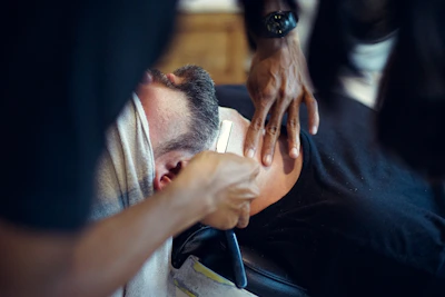 Close-up of a straight razor shave with lather on a customer's face.
