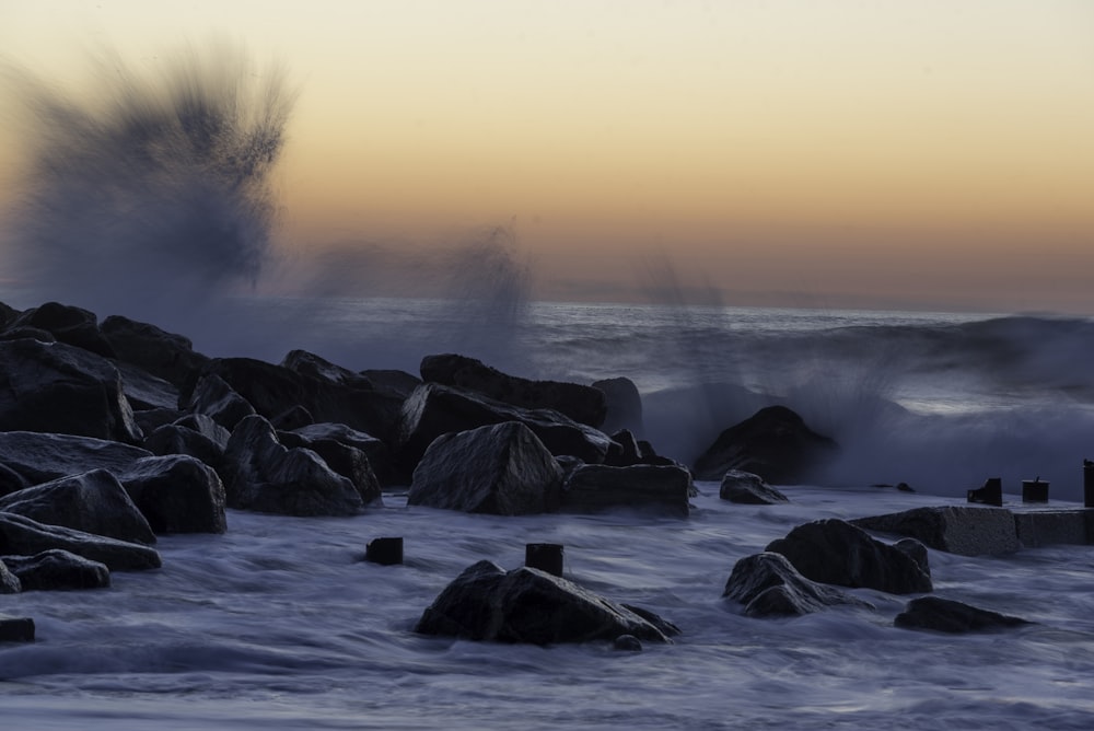 black rocks of splashing body of water