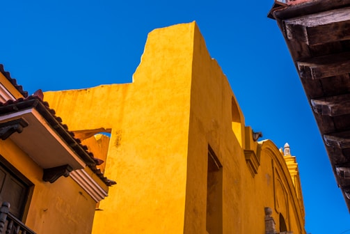 Painter finishing details on a bright yellow residential building.