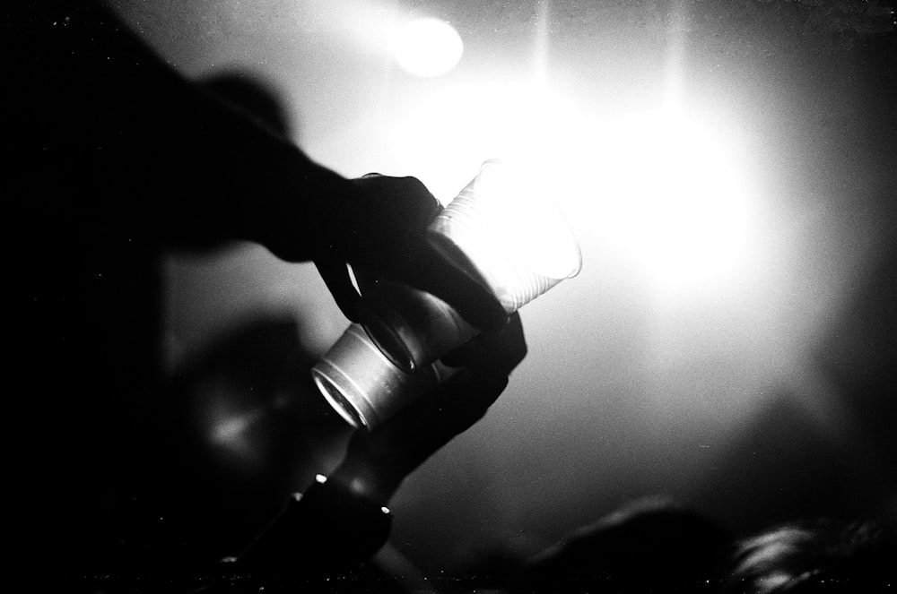 grayscale photography of person holding drinking glass
