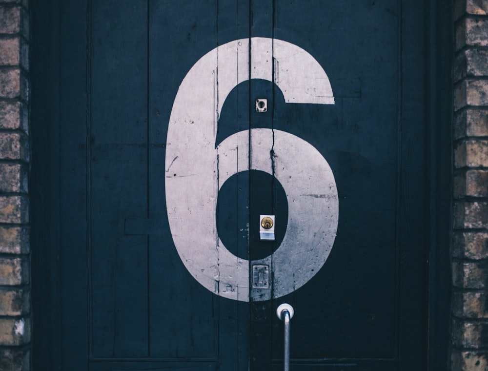 Fotografía macro de puerta de madera azul pintada con el número 6