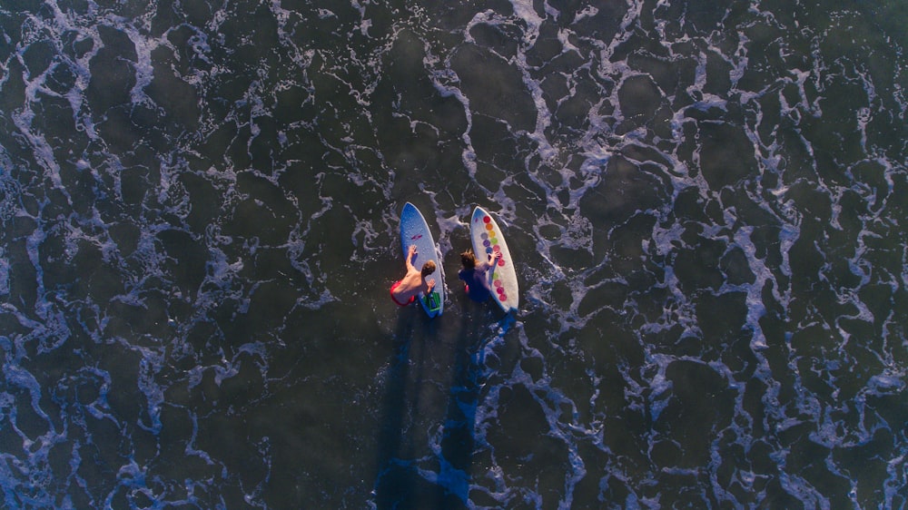 Vista superior de la foto de dos personas con tablas de surf en el agua