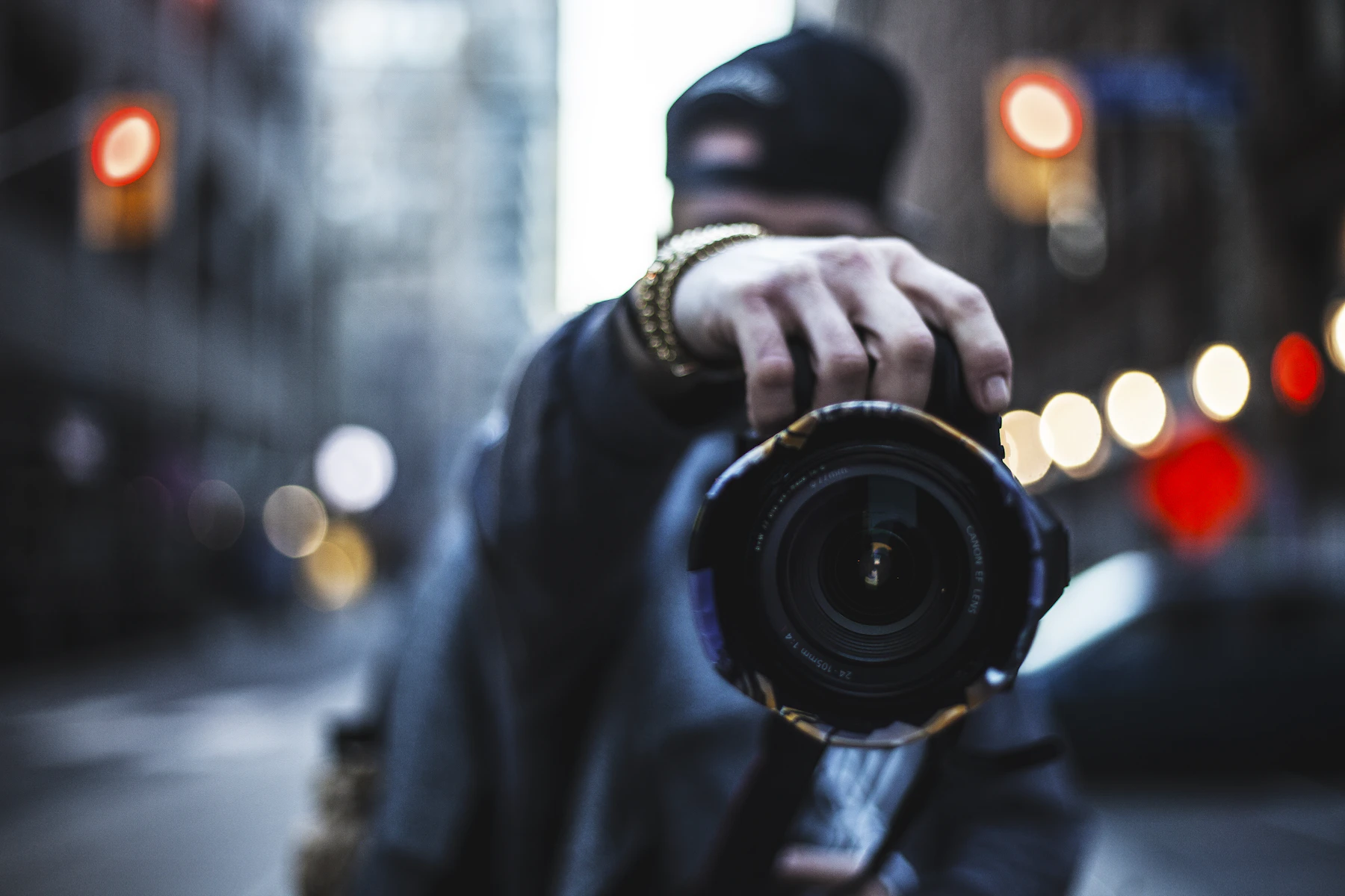 A photographer raising a camera to their eye on a city street at dusk