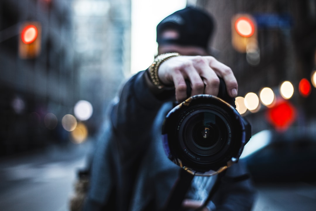 selective focus photography of man holding a camera at the street