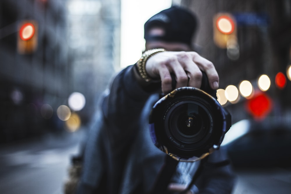 Fotografia di messa a fuoco selettiva dell'uomo che tiene una macchina fotografica per strada