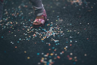 A pair of feet tapping rhythmically on a shiny black floor, surrounded by scattered purple confetti.