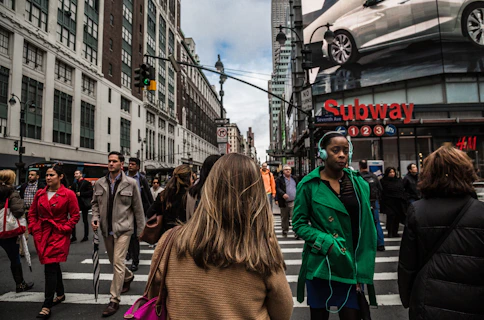 woman wearing green jacket walking on the pedestrian lane during daytime