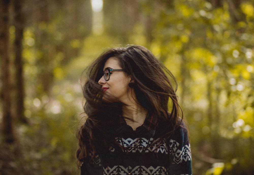 selective focus photography of woman wearing black and white tribal pattern blouse near green trees during daytime