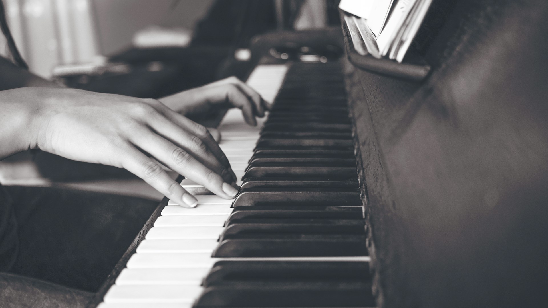 person playing upright piano in sephia photography