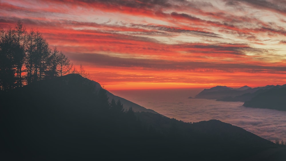 Foto da silhueta da montanha perto do corpo de água durante o pôr do sol