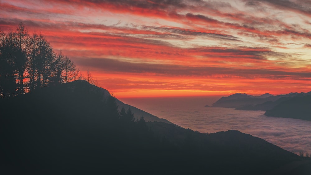 Silhouettenfoto eines Berges in der Nähe eines Gewässers während des Sonnenuntergangs