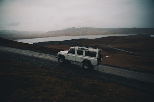 white sport utility vehicle running on road near field in Dyrhólaey Arch Iceland
