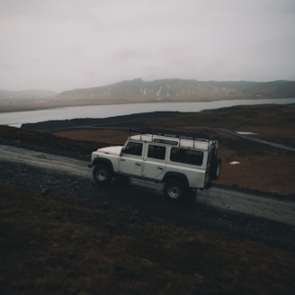 white sport utility vehicle running on road near field