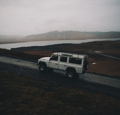 white sport utility vehicle running on road near field