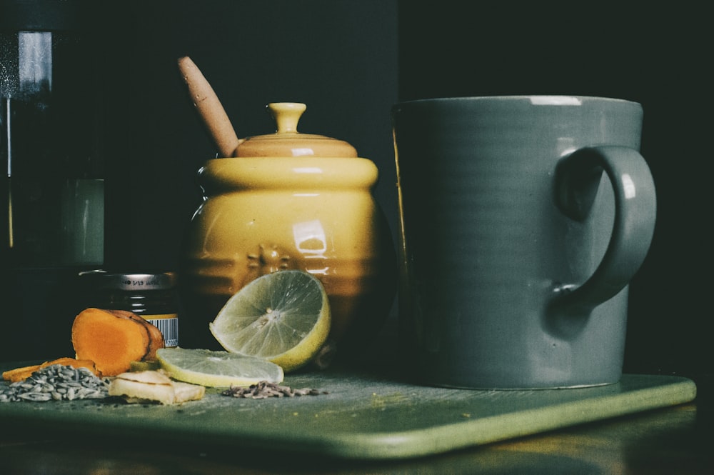 beige ceramic jar beside grey ceramic pitcher and sliced lemon fruit