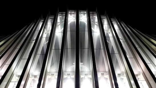 A sleek, modern construction site at dusk with steel beams and glowing blue accent lights highlighting the structure.