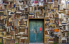 blue wooden door surrounded by book covered wall