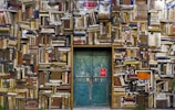 blue wooden door surrounded by book covered wall