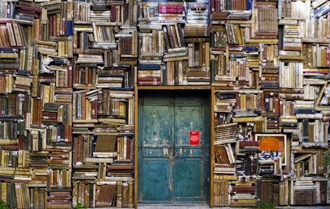 blue wooden door surrounded by book covered wall