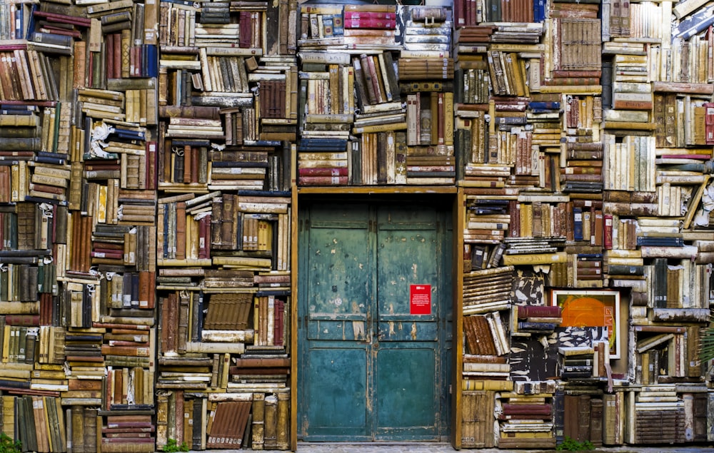 blue wooden door surrounded by book covered wall