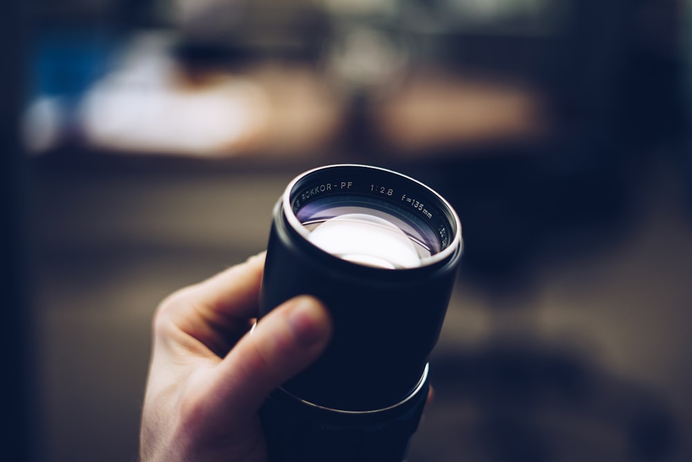 person holding black camera lens