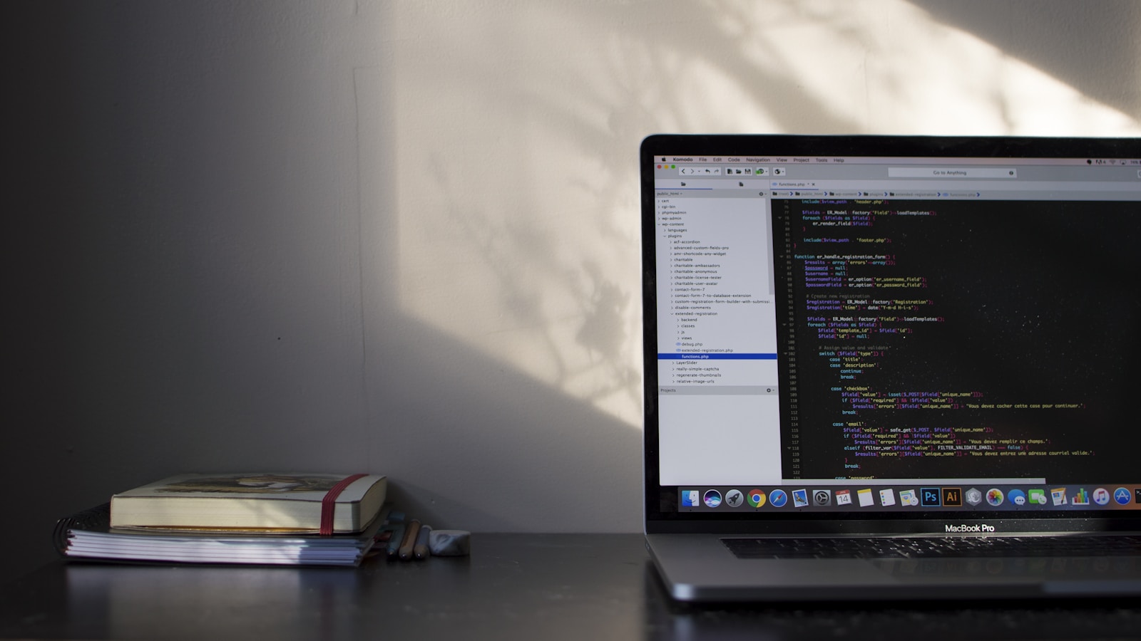 A laptop displaying source code beside notebooks on a desk