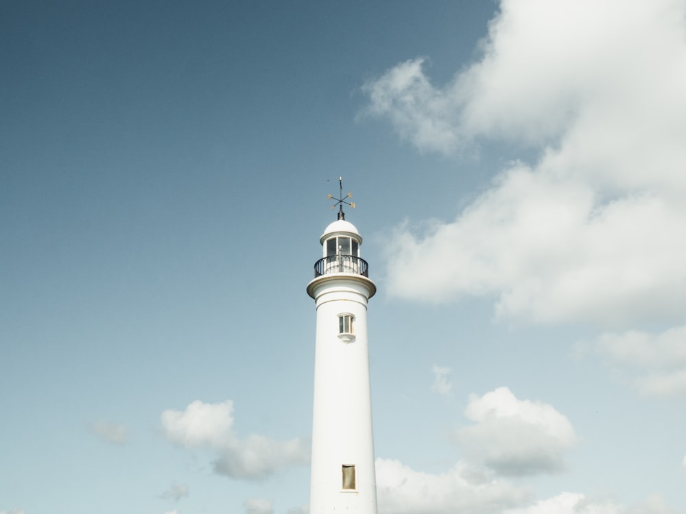 faro blanco bajo nubes cúmulos blancos