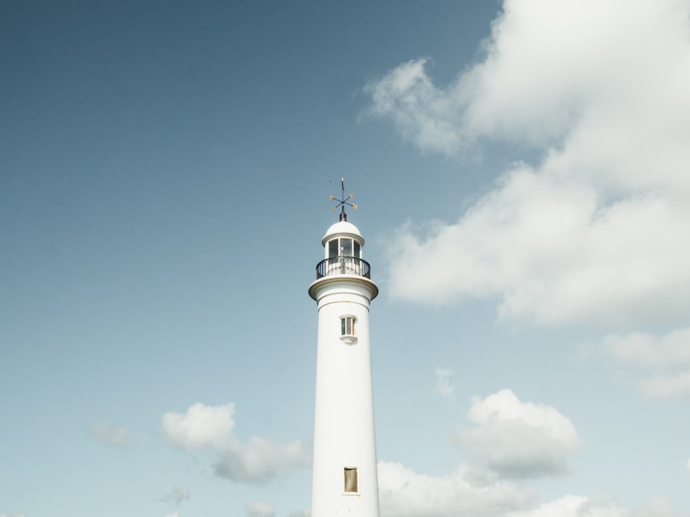 white lighthouse under white cumulus clouds