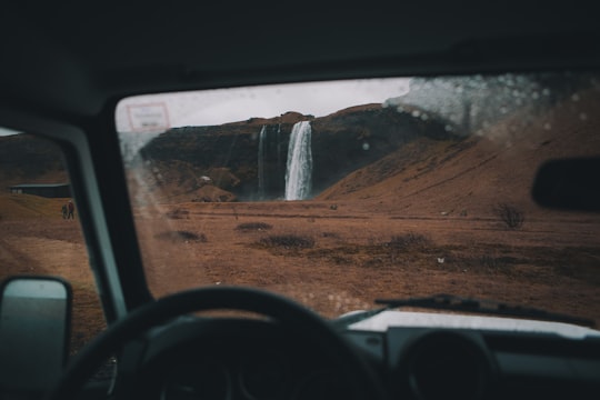 photo of people walking toward waterfalls in Seljalandsfoss Iceland