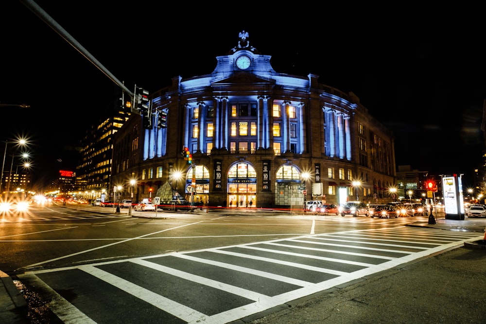 Edifício de concreto azul e branco em cruzamentos com faixa de pedestres à noite