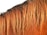 The image displays a close-up of a horse's mane, with strands of hair in a golden brown color cascading down. The texture of the hair is smooth and shiny, suggesting well-maintained equine hair.