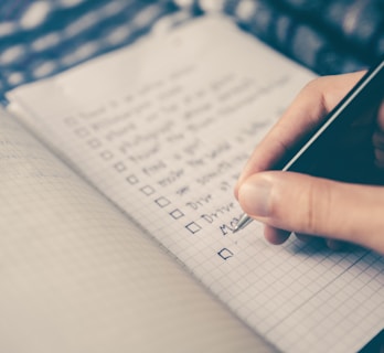 person writing bucket list on book