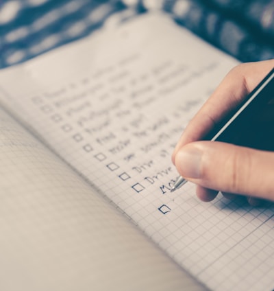 person writing bucket list on book