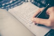 person writing bucket list on book