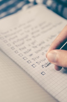 person writing bucket list on book