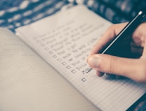 person writing bucket list on book