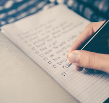 person writing bucket list on book