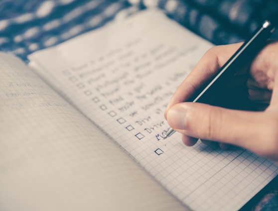 person writing bucket list on book