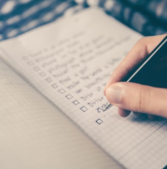 person writing bucket list on book