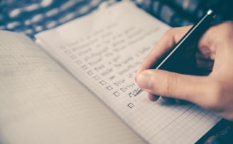 person writing bucket list on book