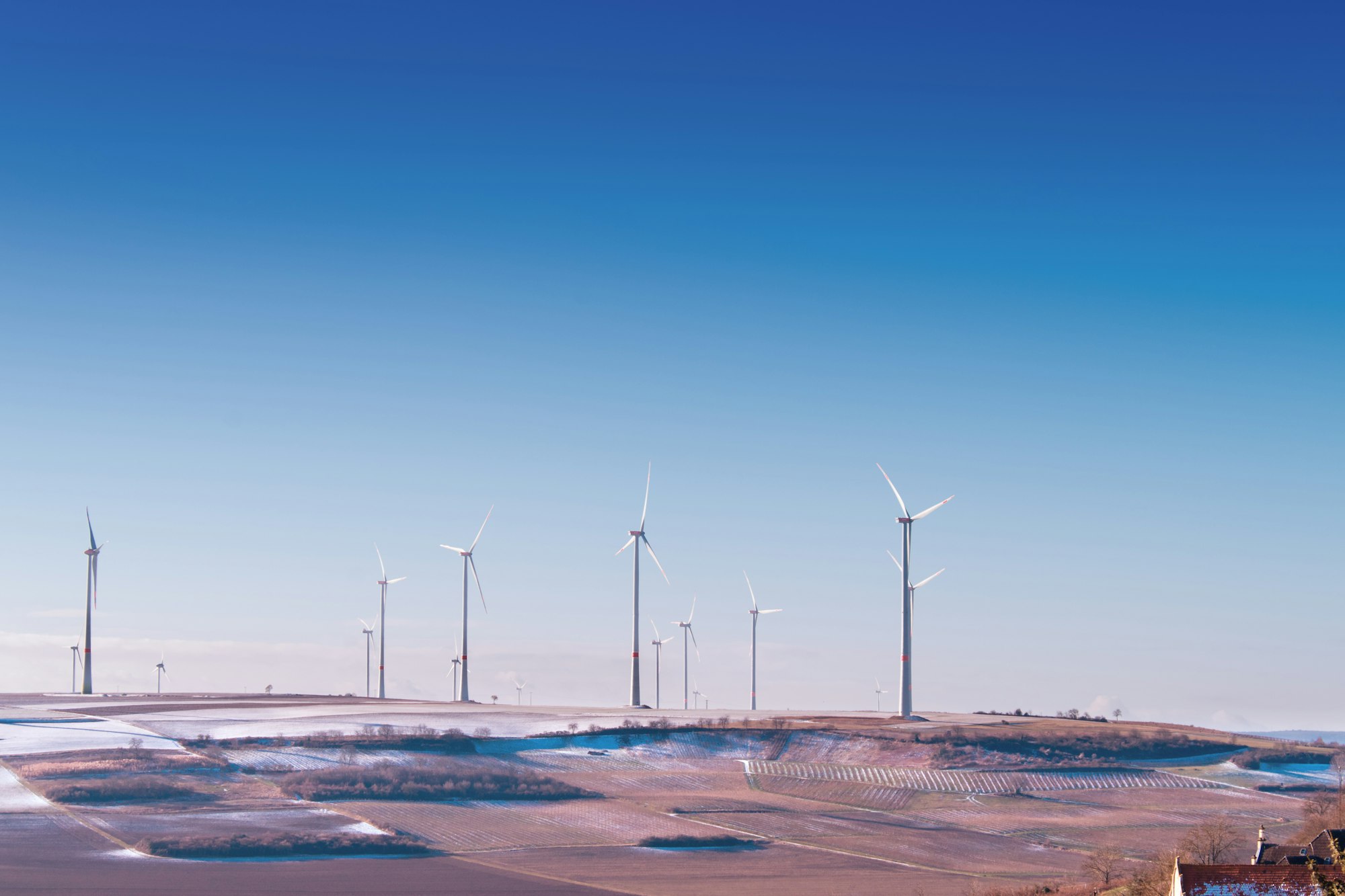 white wind turbine on grey desert under blue and white sky