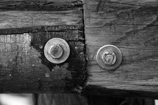 Weathered wood panels connected with metallic bolts, showcasing textures and grains on the surface.